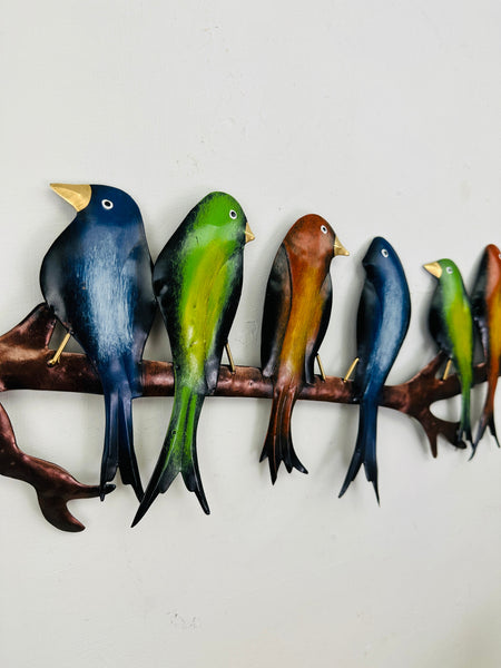 Close-up view of hand-painted metal parakeets in blue, green and copper tones