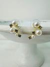 A pair of pearl stud earrings with gold accents and small crystal embellishments displayed on a white stand.