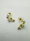 Pair of pearl earrings with gold accents on a light gray background