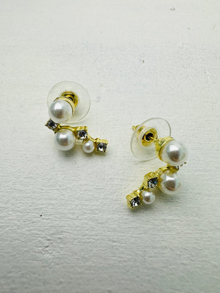Pair of pearl earrings with gold accents on a light gray background