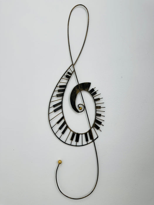 Hand-painted metal treble clef wall sculpture with piano key spiral detailing on a white background