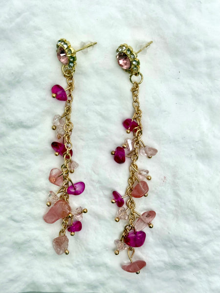 Pair of earrings with pink gemstones on a white textured background