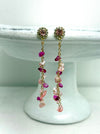 Pair of earrings with pink and gold beads on a white pedestal