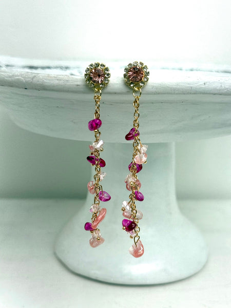 Pair of earrings with pink and gold beads on a white pedestal