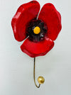 Handmade and hand painted red poppy hook with yellow and antique gold detailing, mounted on a wall.