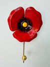 Handmade red poppy flower metal wall hook with gold detailing on white background.