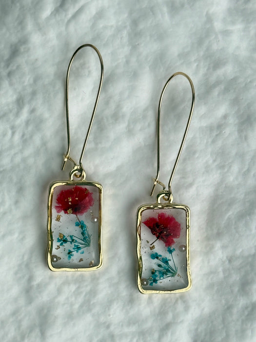 Pair of earrings with floral design on a textured surface