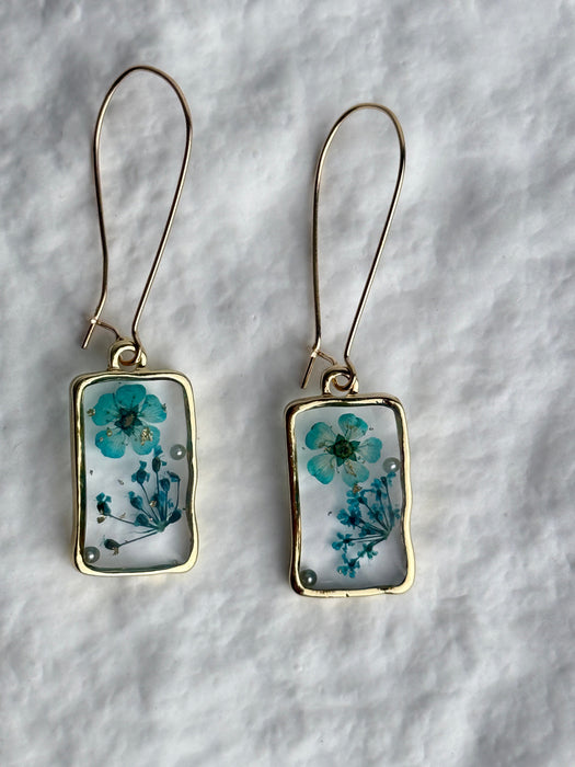 Pair of earrings with floral design on a textured surface