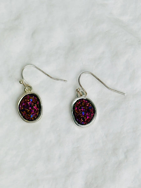 Pair of earrings with purple and pink druzy stones on a white background