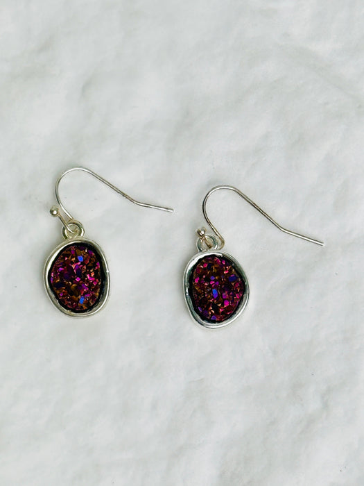 Pair of earrings with purple and pink druzy stones on a white background