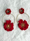 Red floral hoop earrings on a textured white background