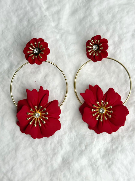 Red floral hoop earrings on a textured white background