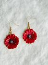 Red flower-shaped earrings with gold accents on a white background