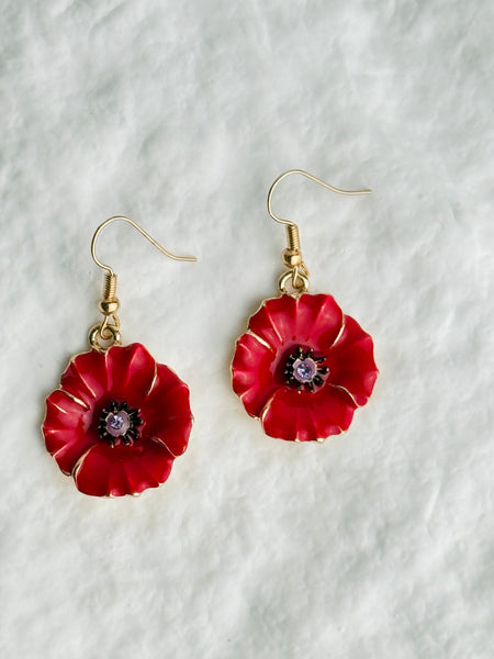 Red flower-shaped earrings with gold accents on a white background