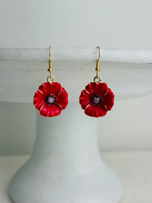 Red flower-shaped earrings on a white stand with a white background