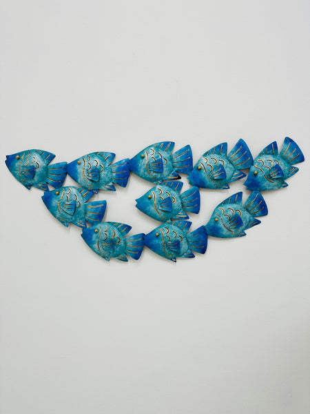 Hand-painted blue reef fish shoal wall art made from recycled metal, displayed on a white background.