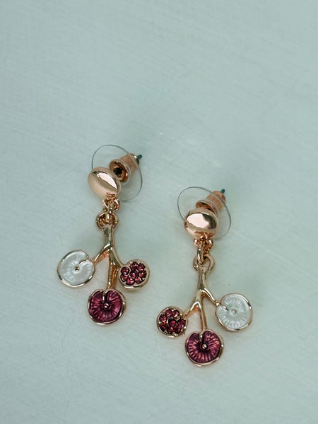 Rose-gold floral enamel drop earrings with gold tone finish, displayed on a white table.