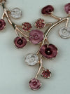 Close-up of rose gold floral enamel necklace with gold-tone chain.