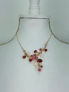 Rose gold floral necklace with enamel flowers in soft pink, deep rose and pearl tones, and small pink crystal accents on brach style design, displayed on a mannequin.