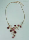 Rose gold floral necklace with enamel flowers in soft pink, deep rose and pearl tones, and small pink crystal accents on brach style design, displayed on a table.