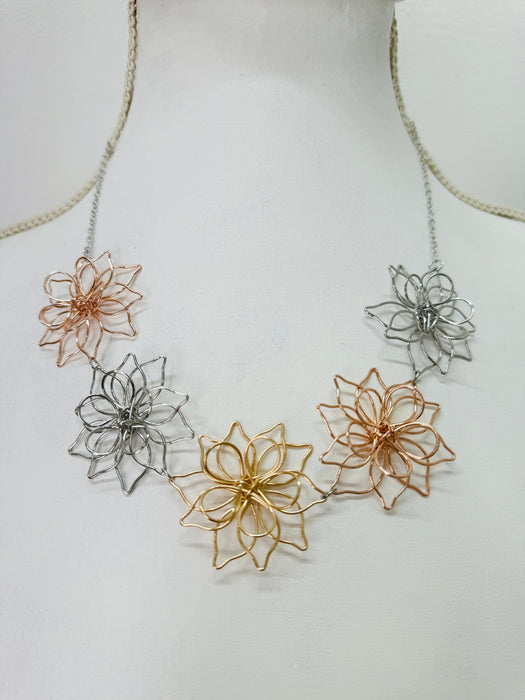 Necklace with floral pendants in gold, silver, and rose gold on a white background