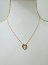 A rose gold necklace with a double heart design and a crystal detail in the center, displayed on a mannequin.