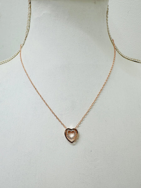 A rose gold necklace with a double heart design and a crystal detail in the center, displayed on a mannequin.