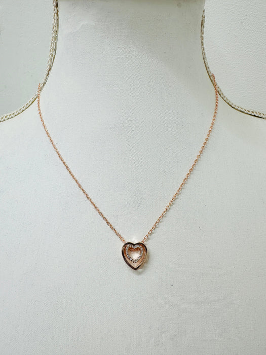 A rose gold necklace with a double heart design and a crystal detail in the center, displayed on a mannequin.