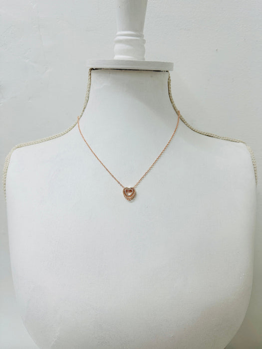 rose gold necklace with a heart pendant on a mannequin bust against a white background