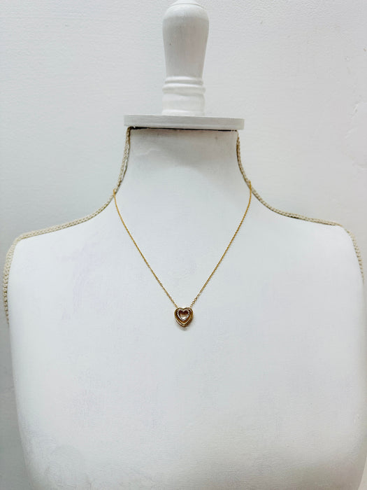 Gold necklace with a heart pendant on a mannequin bust against a white background