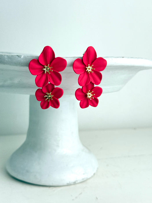 rose red flower-shaped earrings on a white cake stand.