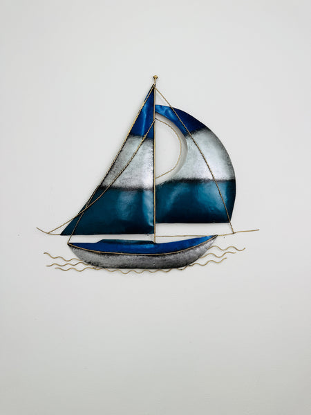Close-up of blue and silver metal sailing boat wall art showing hand-painted metallic details