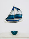 Hand-painted blue and silver metal sailing boat wall sculpture displayed above a small bowl