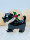 Black dog-shaped brooch with holly leaf and red berry 