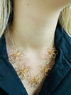A gold-coloured necklace with flower details, displayed on a model