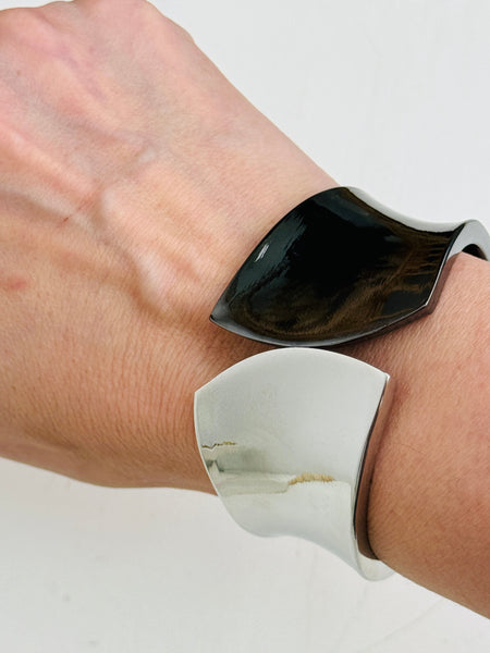 Silver and black tone cuff bracelet with sculptural leaf shape and polished finish