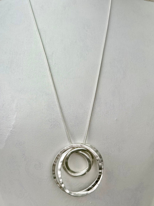 Silver necklace with a circular pendant on a light gray background