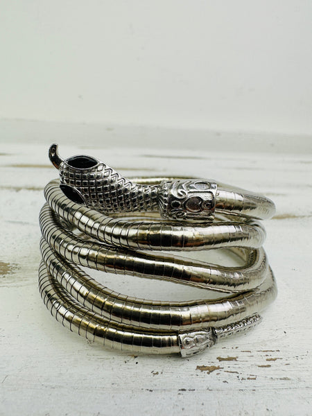 Silver snake-shaped bracelet on a white wooden surface