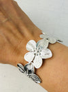 A silver cuff bracelet with blooming floral details, displayed on a model