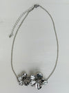 Silver necklace with floral design on a light gray background
