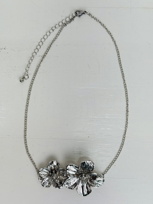 Silver necklace with floral design on a light gray background