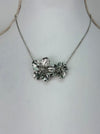 Silver floral necklace on a mannequin with a plain background