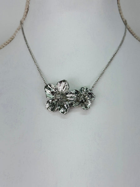 Silver floral necklace on a mannequin with a plain background