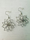 silver flower wire dangle earrings displayed on a table