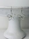 front of silver flower-shaped earrings 