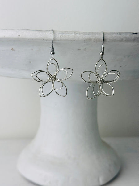 front of silver flower-shaped earrings 