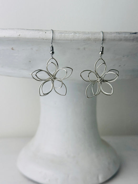 front of silver flower-shaped earrings 