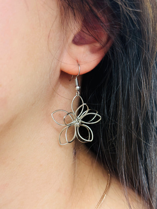 Silver flower-shaped earring displayed on a model