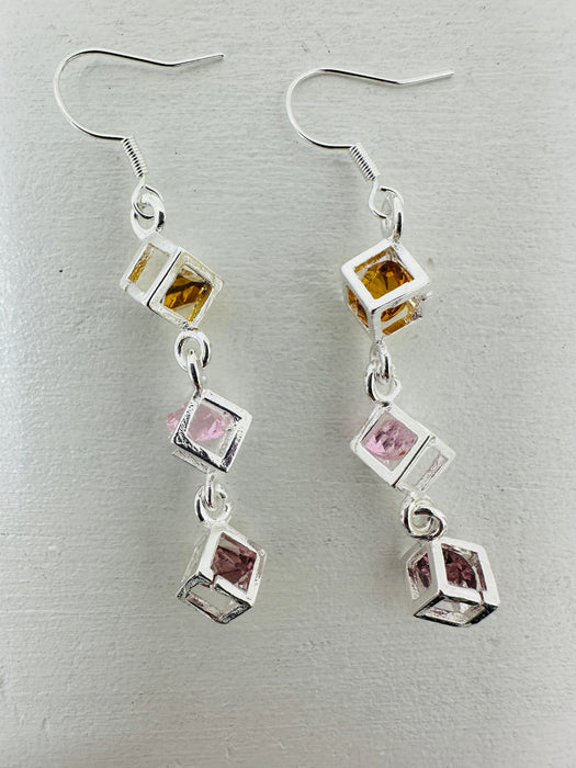 close-up of earrings featuring triple crystal caged cubes with yellow, pink and purple crystal detail.