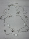Long silver necklace with textured geometric charms displayed on mannequin